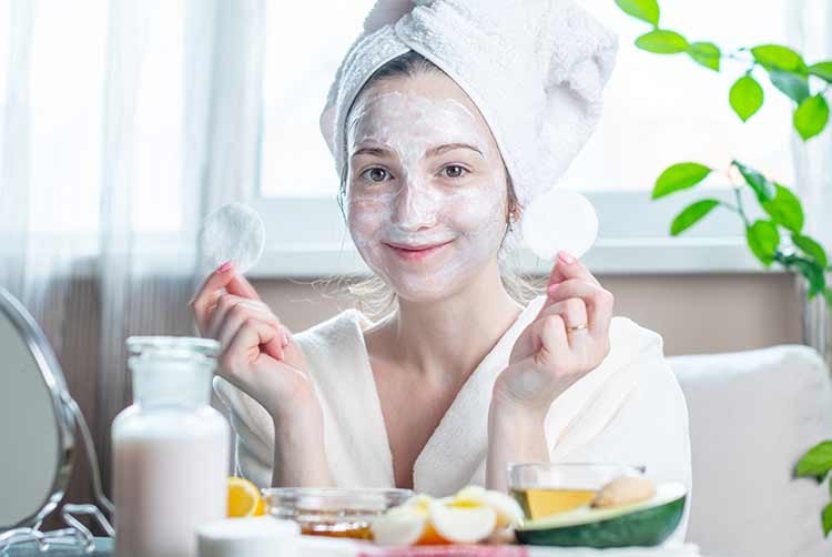 Schöne glückliche junge frau mit natürlicher kosmetischer maske auf ihrem gesicht. konzept hautpflege und spa-behandlungen zu hause
