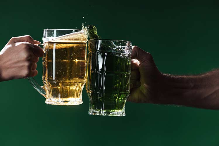 Teilansicht von männern, die mit biergläsern anstoßen, isoliert auf dunkelgrünem, st patrick day concept