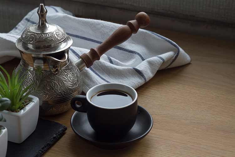 Frisch gebrühter kaffee in cezve, traditionelle türkische kaffeekanne, tasse kaffee, saftig, baumwollhandtuch, freier platz für text.