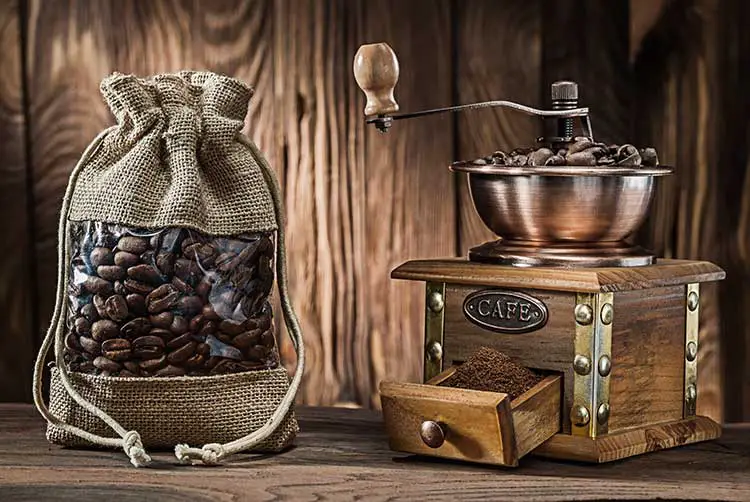 Vintage-sack mit kaffeebohnen und holzmühle auf holzhintergrund