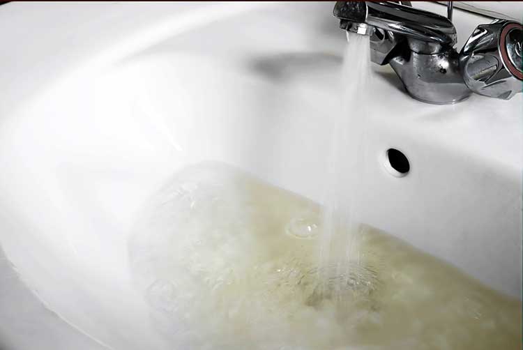 Wasserversorgung von schlechter qualität, fließt vom wasserhahn in das häusliche waschbecken. ungesunde schmutzige, braune farbe.