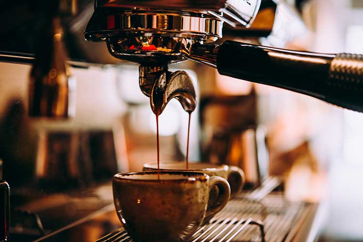 Kaffee, der in einer professionellen espressomaschine in eine tasse gegossen wird