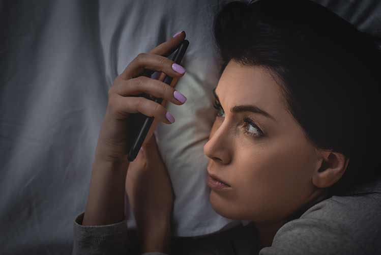 Draufsicht einer wachen frau mit schlaflosigkeit mit smartphone