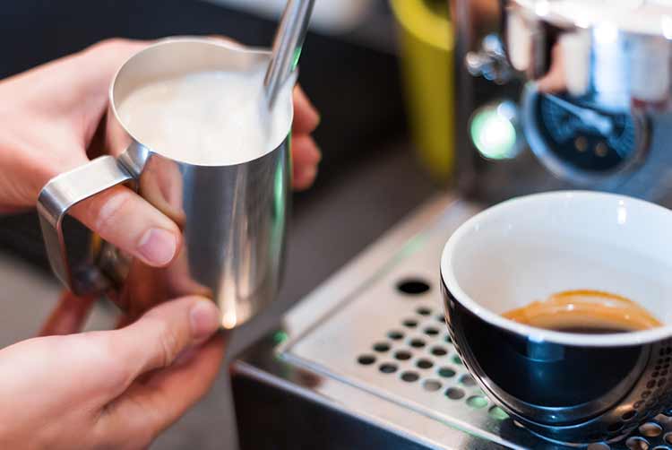 Prozess der vorbereitung, des brauens von americano. nahaufnahme weibliche hände machen kaffee mit professioneller metallmaschine im café. barista erhitzt milch, schlägt schaum mit aufschäumer, dampf. heißgetränke-konzept