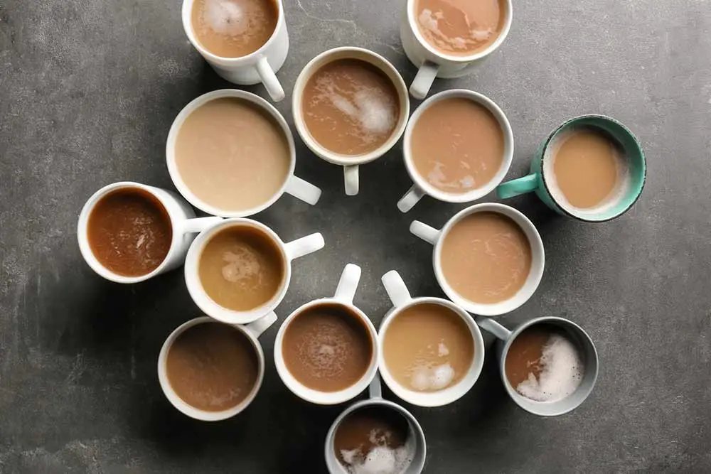 Viele tassen mit leckerem aromatischem kaffee auf grauem tisch, flach gelegt