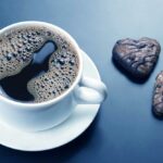 Weiße tasse schwarzen kaffee mit keksen auf dunklem hintergrund. dessert essen