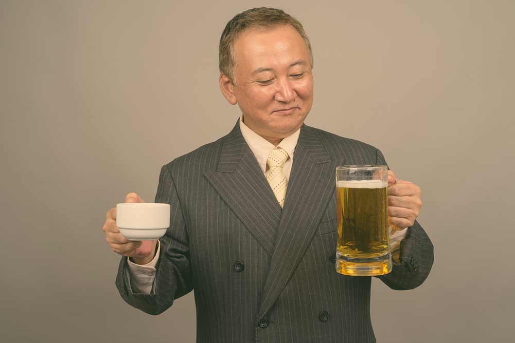 Porträt eines reifen asiatischen geschäftsmannes mit einem glas bier