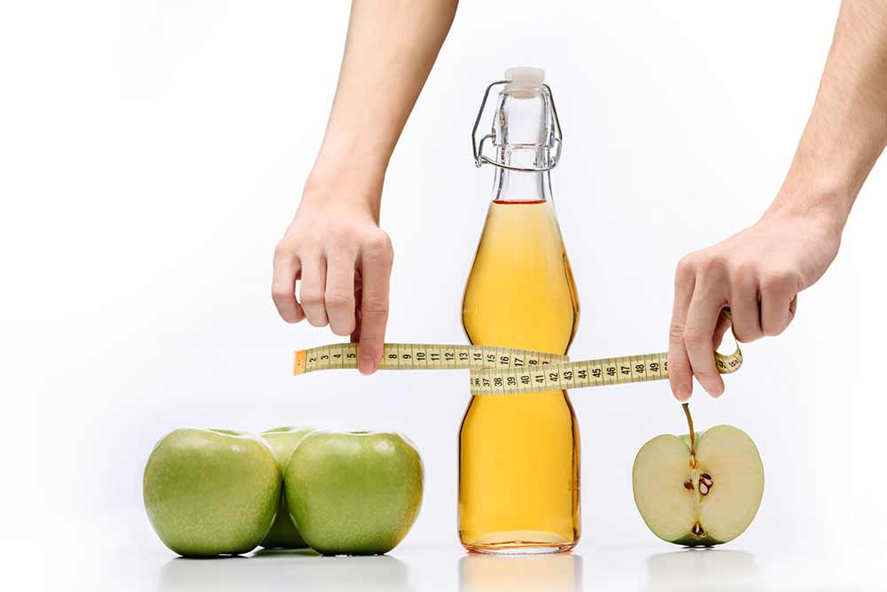 Komposition mit grünen äpfeln, einer flasche apfelsaft und einem schneidermesser in den händen isoliert auf weißem hintergrund mit platz für text. das konzept des abnehmens, der gesunden, vollwertigen ernährung.