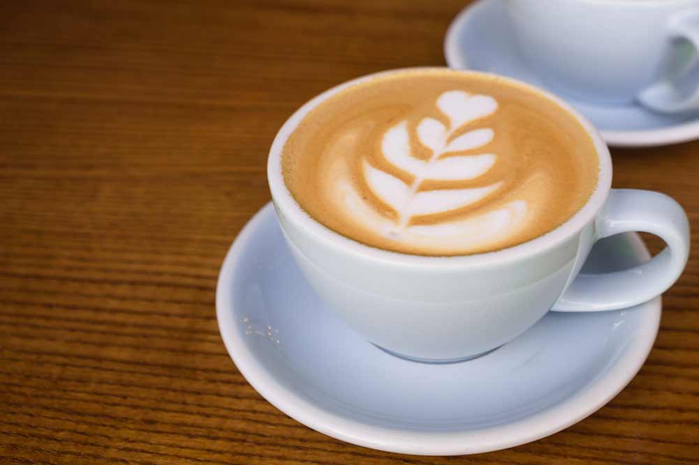 Zwei tassen kaffee auf dem holztisch im café. hellblaue tasse cappuccino.