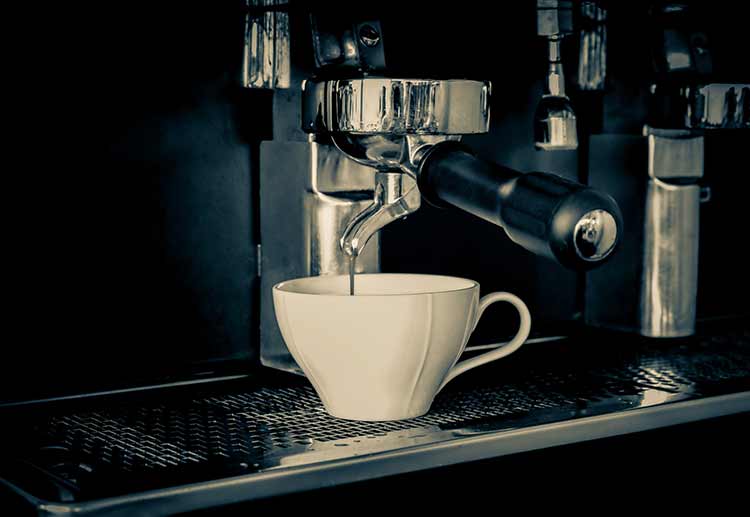 Espresso, der von der kaffeemaschine in die kaffeetasse strömt