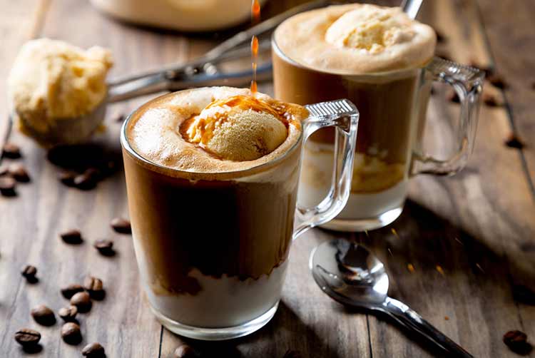 Kaffee auf vanilleeis gießen, um einen affogato-kaffee auf einem rustikalen holztisch zuzubereiten