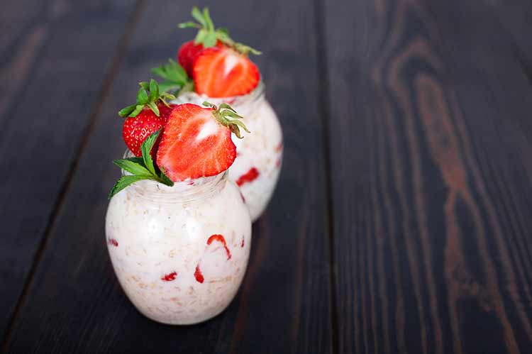 Haferflocken mit joghurt und erdbeeren auf dunklem holzhintergrund. gesundes essen