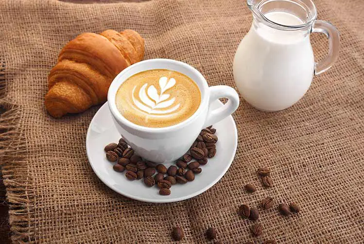 Weiße tasse kaffee auf sackleinenkaraffe mit milchkornkaffee