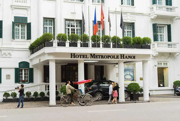 Hanoi, vietnam - 15. märz 2015: äußere vorderansicht von hotel sofitel-legende metropole hanoi mit laufendem cyclo. das sofitel legend metropole hanoi ist eine bekannte französische architektur in vietnam.