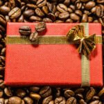 Rote kleine geschenkbox mit schleife auf geröstetem hintergrund der braunen kaffeebohnen.
