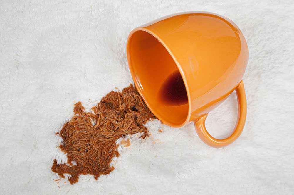 Horizontale aufnahme einer tasse verschütteten kaffees auf weißem teppichboden.