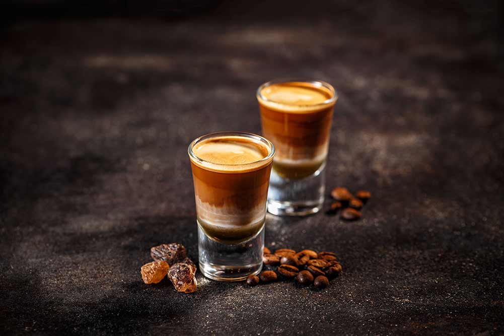 Kaffeecocktail mit schnaps in schnapsgläsern auf dunklem vintage-hintergrund