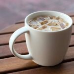Nahaufnahme von gefrorenem latte-cappuccino-kaffeetee in einem becher, holztischhintergrund