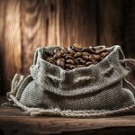 Jahrgang mit kaffeebohnensack auf altem holzschreibtisch und holzhintergrund