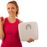 Schöne junge aktive fit frau halten skala als geste nach verlieren gewicht isoliert über weißem hintergrund - gewichtsverlust
