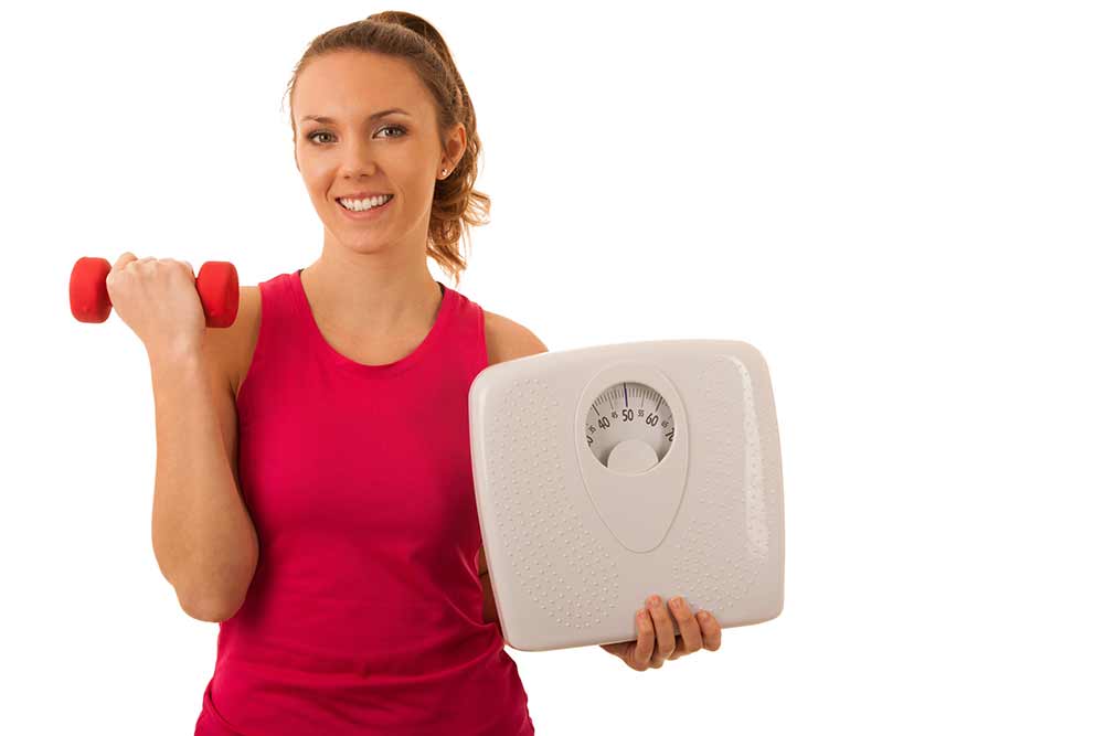 Schöne junge aktive fit frau halten skala als geste nach verlieren gewicht isoliert über weißem hintergrund - gewichtsverlust