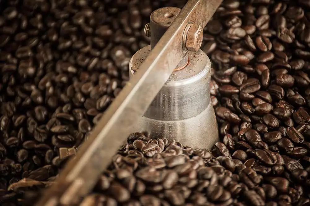 Kaffeebohnen während des röstvorgangs, bewegliches paddel des siebtrichters kühlt die kaffeebohnen nach dem röstvorgang ab. trommelröster