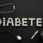 Draufsicht "diabetes"-schriftzug aus zuckerwürfeln mit medizinischen geräten auf schwarz