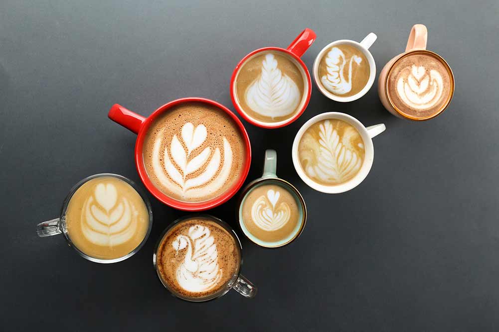 Buch mit kaffeetassen mit verschiedenen getränkesorten und verschiedenen latte-art-schaumdesigns. ansicht von oben, nahaufnahme, kopierbereich, hintergrund.