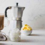 Ketogener keto-diätkaffee gemischt mit kokosnussöl und butter. tasse kaffee und zutaten auf weißem hintergrund.