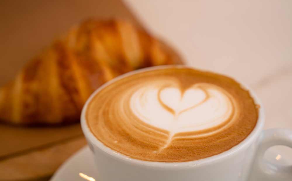Hintergrundbild von cappuccino mit croissant an der seite
