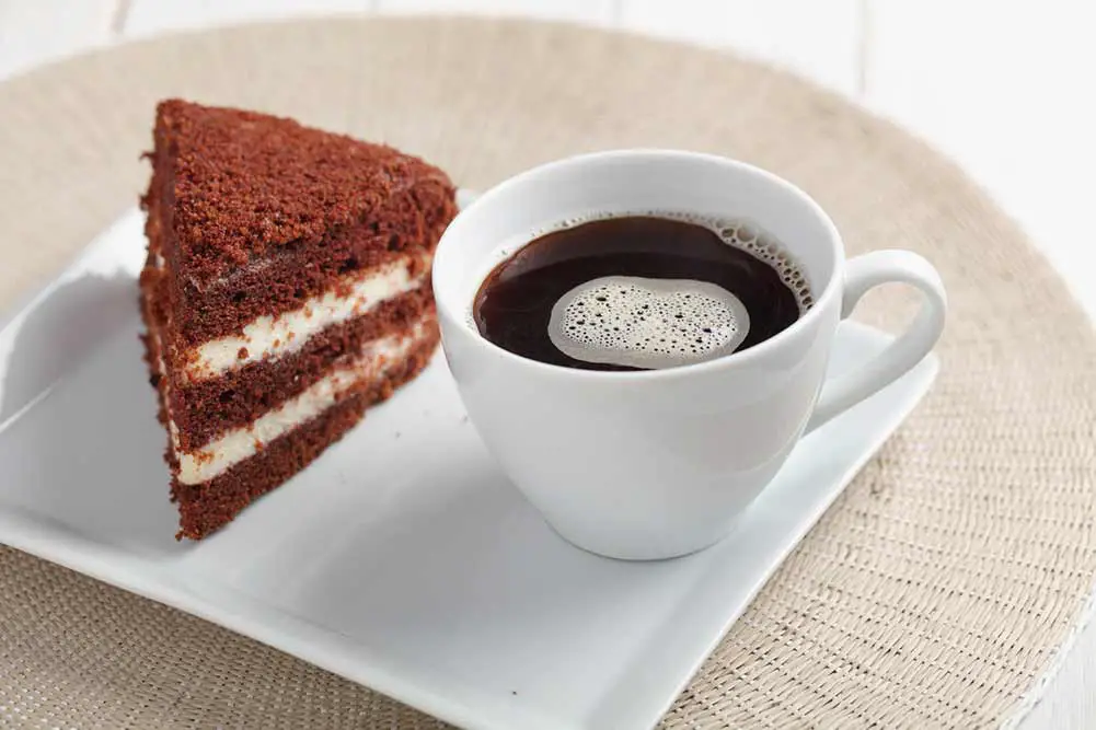 Schokoladen-sauerrahm-kuchen und eine tasse schwarzen kaffee