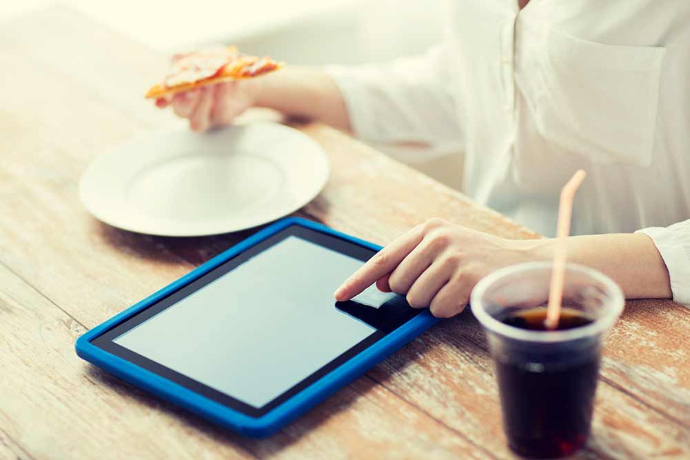Schnellimbiss-, leute-, technologie- und diätkonzept - nah oben von der frau mit tabletten-pc-computer, von pizza und von kolabaum, die bei tisch kalorien zählen