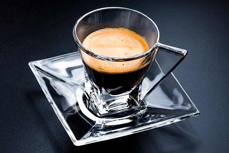 Glastasse espressokaffee mit glasuntertasse auf schwarz