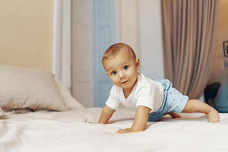 Porträt eines kriechenden babys auf dem bett im schlafzimmer