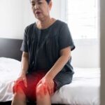 ältere asiatische frau, die an beinschmerzen leidet, frau, die ihr verletztes knie berührt