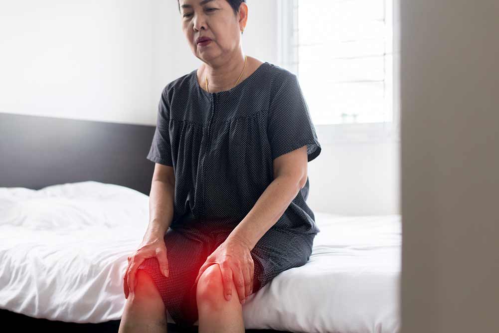 ältere asiatische frau, die an beinschmerzen leidet, frau, die ihr verletztes knie berührt