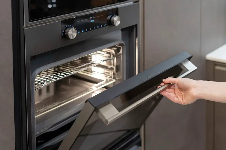 Sedie view foto von frauenhand, die einen neuen modernen einbauofen in einem schwarzen küchenschrank öffnet