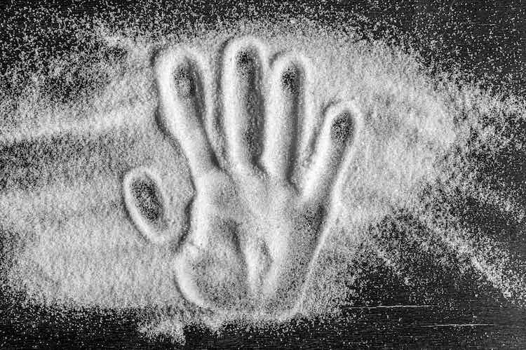 Draufsicht des handabdrucks auf verschüttetem zuckerzuckersand. konzept der ernährung, diabeteskontrolle