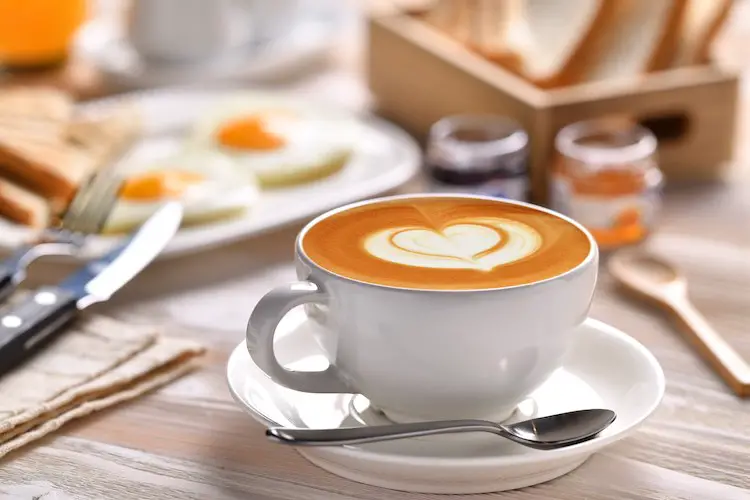 Tasse kaffee latte mit frühstück auf holztisch