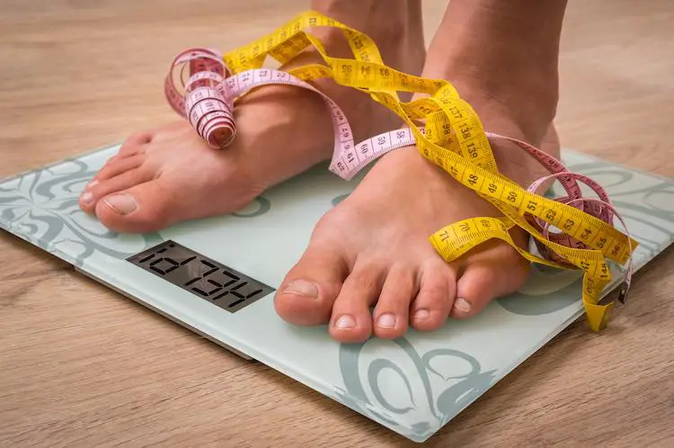 Weibliche füße auf persönlichen skalen mit word help! - fettleibigkeit und diät-konzept