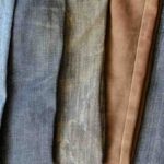 Mehrfarbige jeans auf ladentheke. vorführung verschiedener farbnuancen von jeanshosen. moderne freizeitkleidung. draufsicht schräg. selektiver fokus.