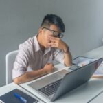 Der junge asiatische angestellte fühlt sich müde und frustriert von seinem job