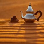 Arabische teekanne und datteln in der wüste bei einem wunderschönen sonnenuntergang als symbol für ramadan