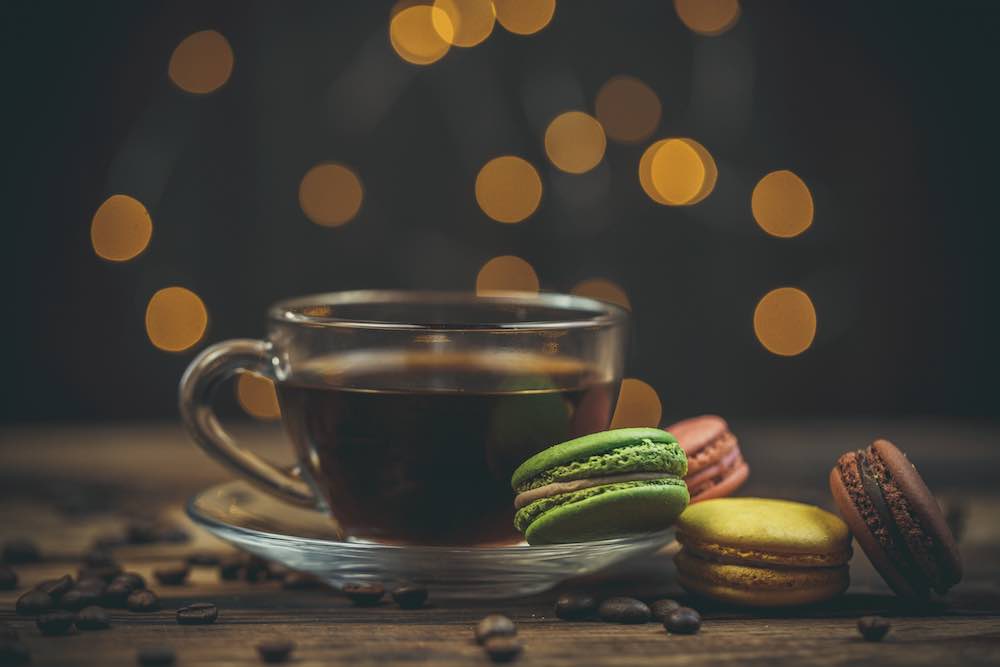 Leckere makronenkekse mit kaffee auf einem holztisch in warmen farben mit schönem bokeh