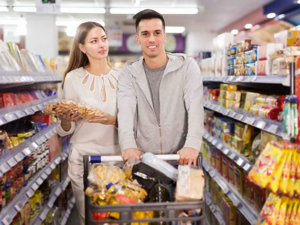 Porträt eines familienpaares, das cracker und snacks in der lebensmittelabteilung des supermarkts einkauft