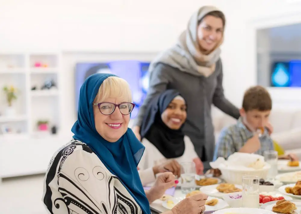 Moderne multiethnische muslimische familie, die es genießt, während eines ramadan-festes zu hause gemeinsam ein iftar-abendessen zu essen