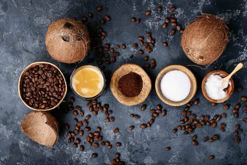 Kugelsicherer kaffee serviert mit gemahlenen und ganzen kaffeebohnen, kokosnüssen, kokosöl auf dunklem texturhintergrund. ansicht von oben, flach liegend. platz kopieren