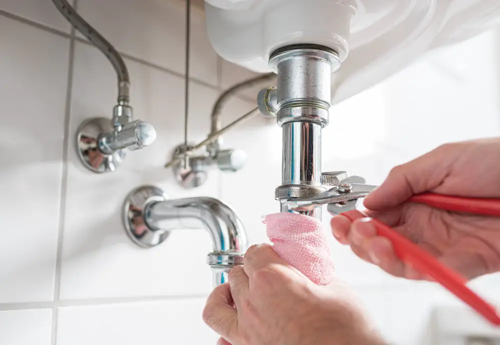 Mann repariert waschbeckenfalle mit verstellbarer rohrzange im badezimmer