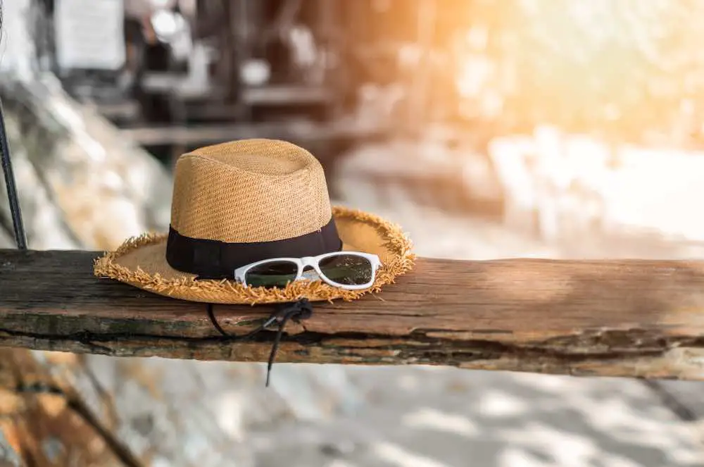 Hut und sonnenbrille oder sommeraccessoires auf schaukel im sonnenlicht am strand. hintergrund des urlaubskonzepts