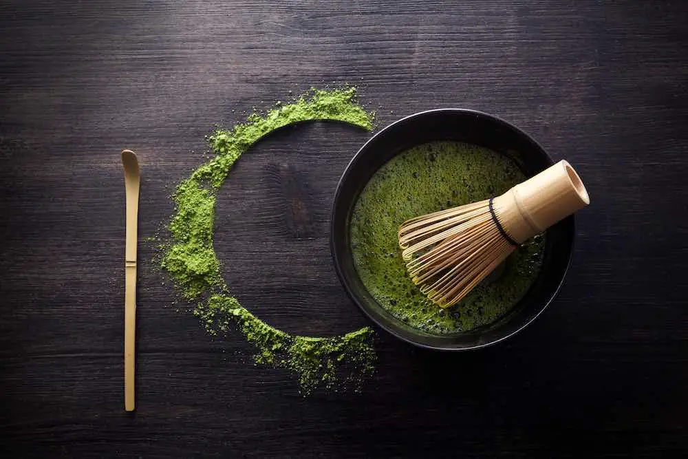Matcha-pulver. organische grüne matcha-teezeremonie. gesundes getränk. traditionelles japanisches getränk auf schwarzem holzhintergrund
